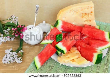 Ripe watermelon, cheese and cottage cheese, served in simple country style with flowers. Healthy food for lunch or snack. Selective focus