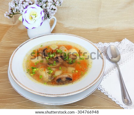 Chicken noodle soup with mushrooms and green onions. Served with flowers.  Mediterranean healthy food. Selective focus