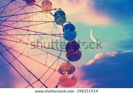 Vintage photo with ferris wheel against the moon colorful sky