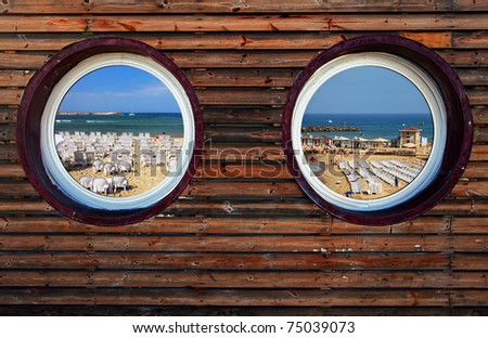 Two round windows of the wooden house with view on perfect beach of the Mediterranean sea