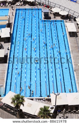 Top view on pool with blue water and floating people