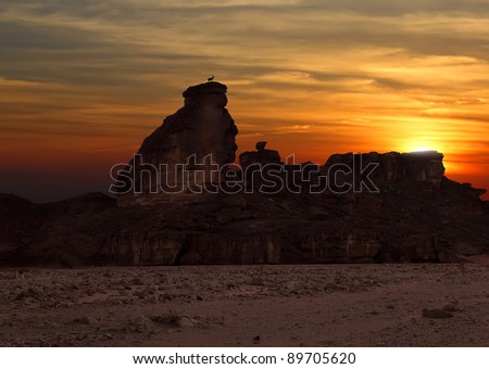 Mountains and a mountain goat standing at the top on the  sunset background in stony desert