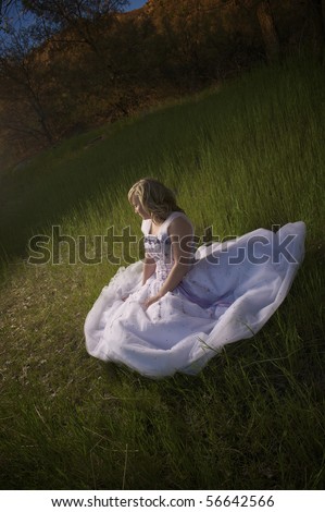 Young pretty blonde girl wearing prom dress outdoors at sunset