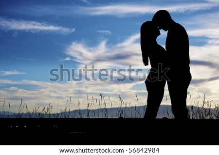 A couple kissing together at the setting of the sun