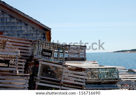 Lobster traps are piled up near this building by the sea