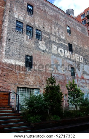 The painted sign is fading from this brick warehouse facade located along New York City\'s High Line Park
