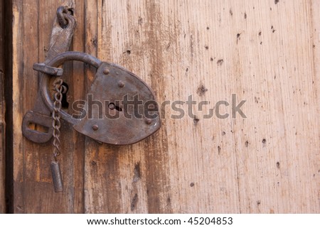 A rusty lock on a wooden gate