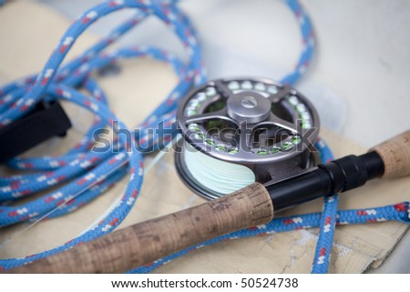 Cropped close-up of a fly-fishing rod and reel in a boat. Horizontal format.