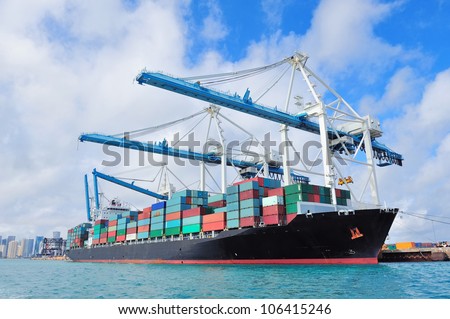 Cargo ship at Miami harbor with crane and blue sky over sea.