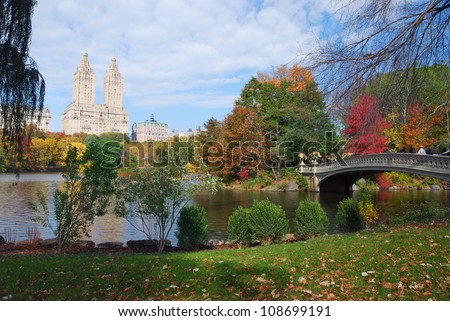 New York City Central Park panorama view in Autumn with Manhattan skyscrapers and colorful trees with Rainbow Bridge over lake with reflection.