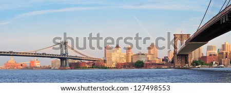Manhattan Bridge and Brooklyn Bridge panorama over East River viewed from New York City Lower Manhattan waterfront at sunset.