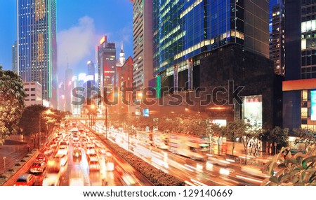 Hong Kong street with busy traffic and skyscraper office at dusk.