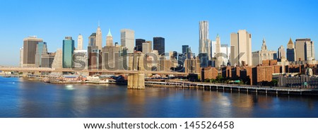 New York City Manhattan skyline panorama with Brooklyn Bridge and skyscrapers over Hudson River in the morning after sunrise.