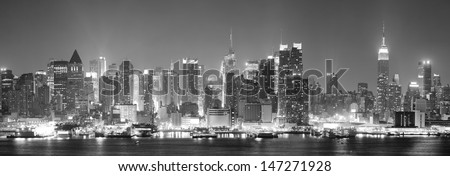 New York City Manhattan Midtown Skyline Black And White At Night With Skyscrapers Lit Over Hudson River With Reflections.