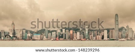 Urban architecture in Hong Kong Victoria Harbor with city skyline and cloud in the day with yellow tone.