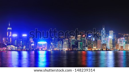 Hong Kong city skyline at night over Victoria Harbor with clear sky and urban skyscrapers.
