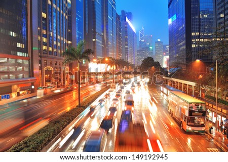 Hong Kong Street With Busy Traffic And Skyscraper Office At Dusk.