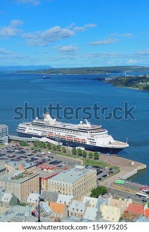 Cruise ship in river in Quebec City with blue sky and historical buildings.