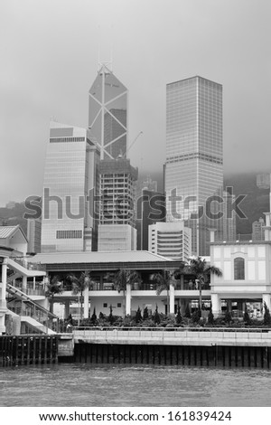 Hong Kong urban architecture over sea with skyscrapers in black and white.