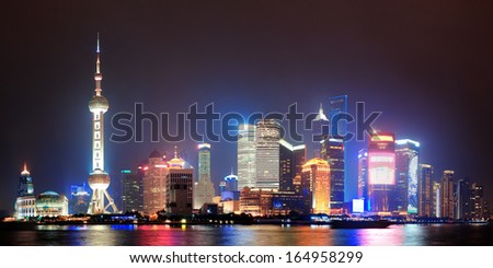 Shanghai night panorama over Huangpu River with skyline and urban buildings.