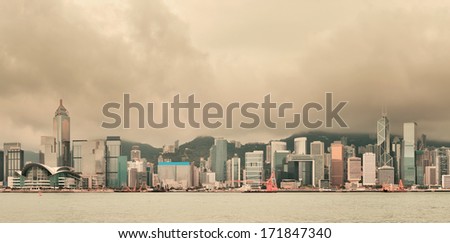 Urban architecture in Hong Kong Victoria Harbor with city skyline and cloud in the day with yellow tone.