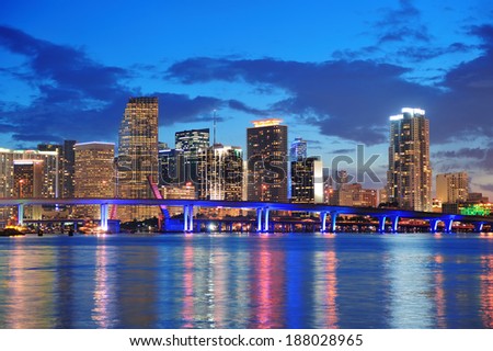 Miami city skyline panorama at dusk with urban skyscrapers and bridge over sea with reflection