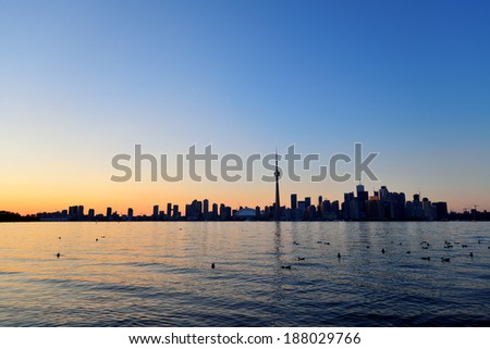 Toronto sunset silhouette at dusk over lake with urban architecture.