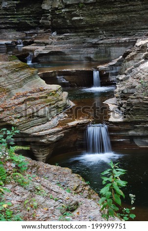 Waterfall in woods with rocks and stream in Watkins Glen state park in New York State