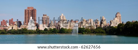 New York City Central Park panorama in Manhattan over lake with skyscrapers and fountain with trees and reflection.