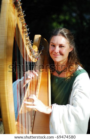 NEW YORK CITY - OCT 3: Beautiful woman musician playing harp in New York Medieval Festival. October 3, 2010 in Ft. Tryon park; Manhattan, New York City.