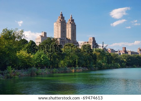 New York City Central Park urban Manhattan skyline with skyscrapers and trees lake reflection with blue sky and white cloud.