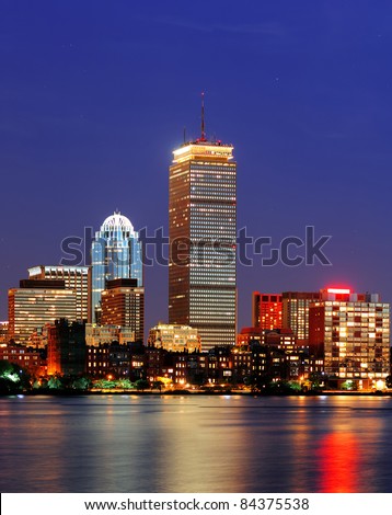 Boston city skyline at dusk with Prudential Tower and urban skyscrapers over Charles River with lights and reflections.