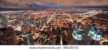 Chicago urban skyline panorama aerial view with skyscrapers and cloudy sky at dusk with lights.