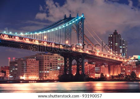 Manhattan Bridge closeup over East River at night in New York City Manhattan with lights and reflections.