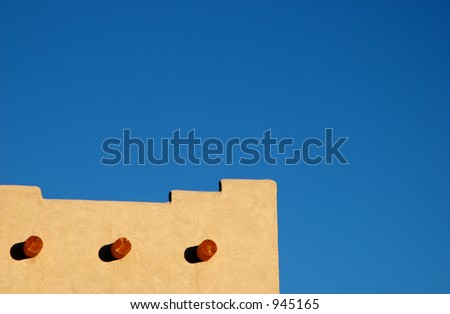 Detail of adobe building against blue sky with lots of negative space to drop in text