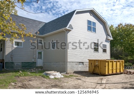 Home construction with gabled roof design and trash receptacle