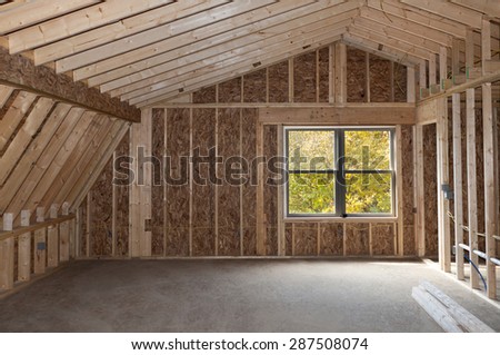 Room addition construction with pitched ceiling and autumn trees view window
