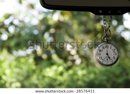 Antique pocket watch hanging from mirror showing five oclock