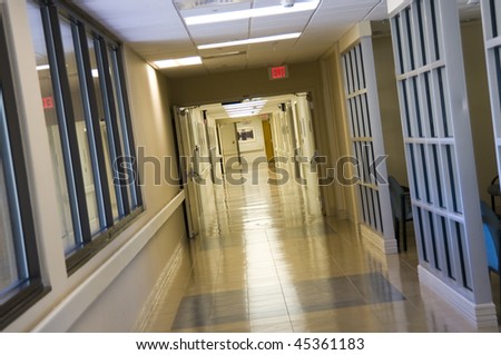 Long lighted hospital hallway with exit sign