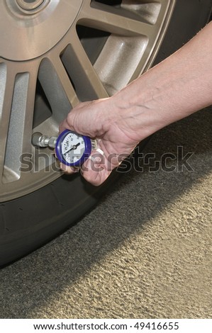 Woman checking her tire pressure to help increase her  gas mileage gauge indicates low pressure