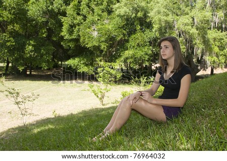 Beautiful teenage girl outdoors sitting and day dreaming