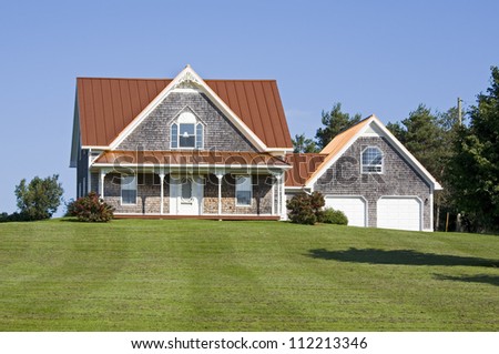 A large country house with a bronze steel roof and an expansive lawn.