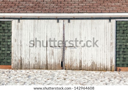 Old weathered barn doors on a rustic barn in winter.