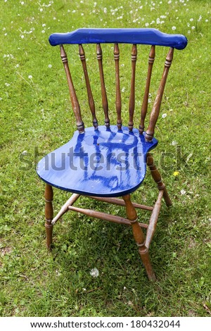 Old fashioned wooden chair paritally painted a shiny gloss blue.