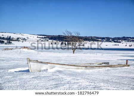 Old wooden rowboat buried in snow in rural Prince Edward Island.