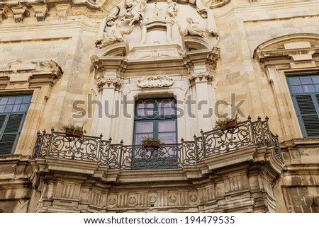 A typical Maltese balcony with a fancy wrought iron railing.