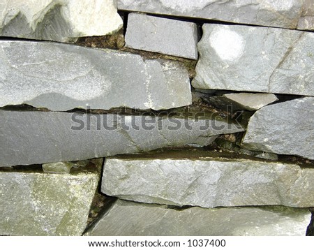 Flat stones stacked in an old mossy stone wall