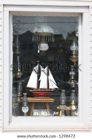Shop window featuring items for sale such as model boats and antique glass lamps.