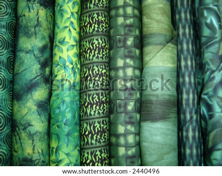 Various bolts of green fabric on display.