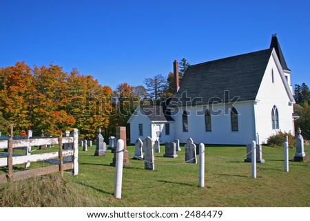 A small country church backed by the fall trees,  with its little cemetery.